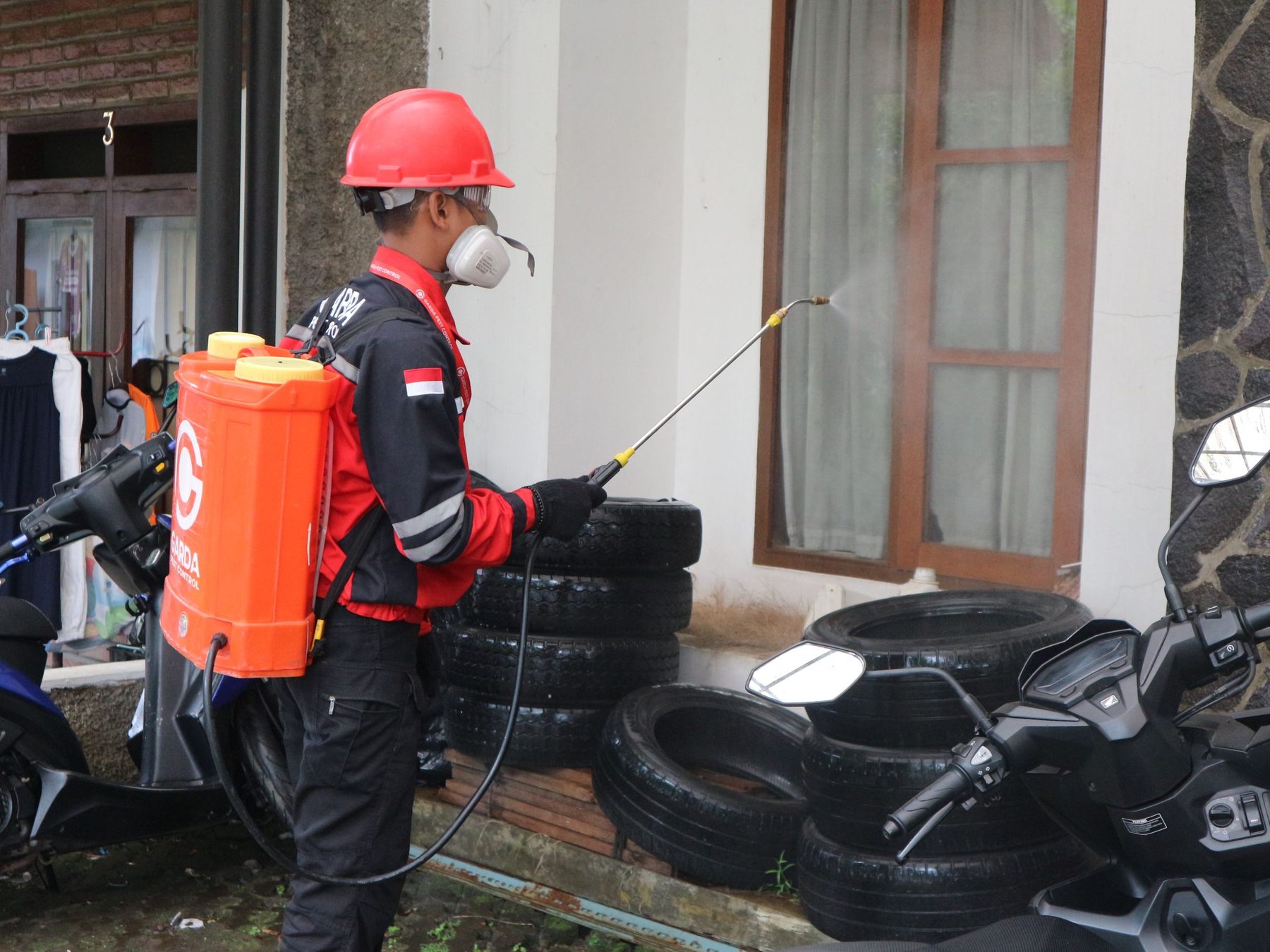 A pest control technician treating the exterior of a building